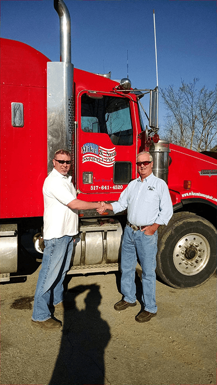 Father and son handshake in front of red Kenworth with Mike & Son door logo